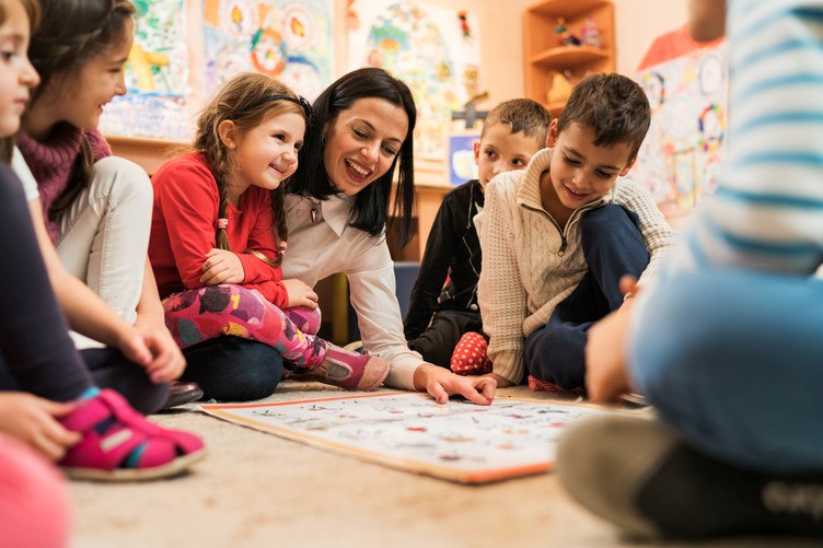 A Celebree School teacher reads a picture book to a group of young children seated in a colorful classroom during story time.